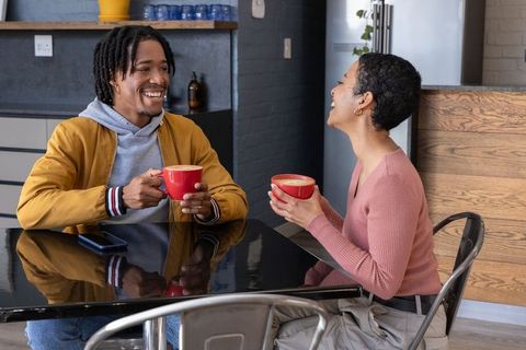 Young african american couple laughing over lattes in modern cafe