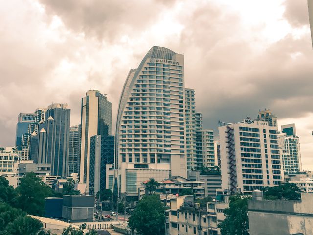 Photo showcases the dynamic skyline featuring the Pullman Hotel and other high-rise buildings under a cloudy sky. Ideal for illustrating modern cities, urban development, and hospitality industry. Use in real estate marketing, travel brochures, and articles about city infrastructure.