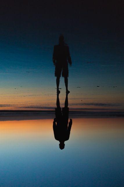 Silhouette of Man Reflecting on Calm Water During Dusk at Beach - Download Free Stock Images Pikwizard.com