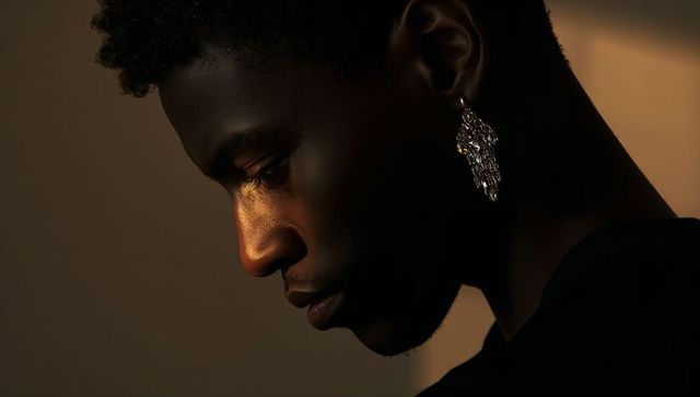 Moody profile portrait african american man wearing ornate dangling earring, warm light