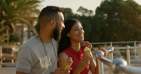 Couple enjoying ice cream in sunlit park