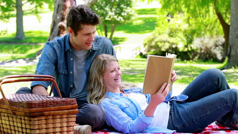 Happy Couple Relaxing and Reading Book in Park