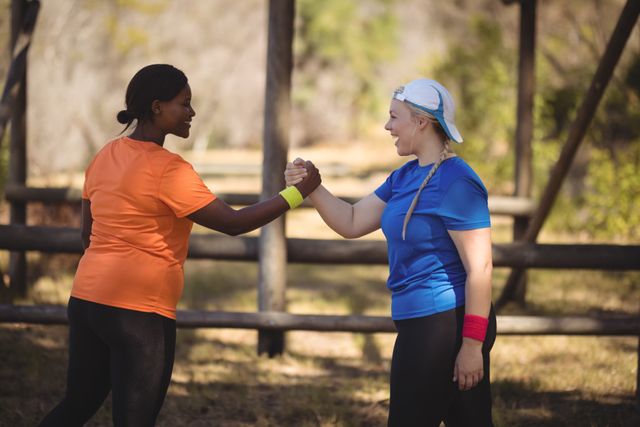 Happy friend holding hands during obstacle course in boot camp