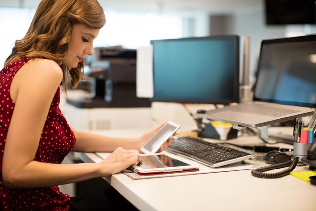 Side view of young businesswoman using digital tablet in office