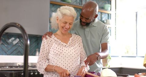 Senior woman and friend preparing vegetables together in kitchen