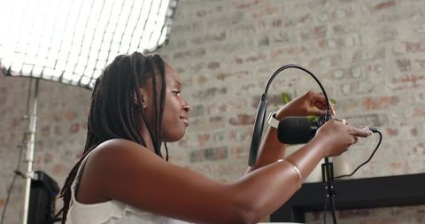 African american woman adjusting microphone for podcast recording in loft studio