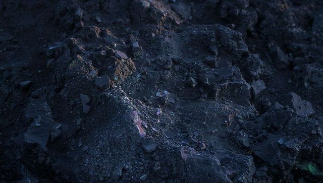 Iridescent craggy volcanic outcrop featuring metallic flecks and coarse gravel at dusk