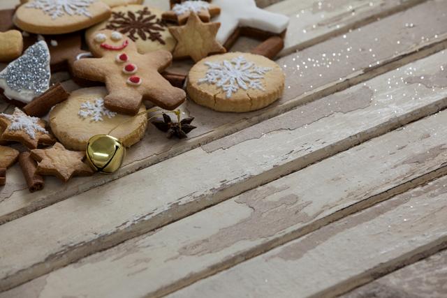 Assorted Christmas cookies, including gingerbread men and star-shaped cookies, decorated with icing and sprinkles, are arranged on a rustic wooden plank. This festive scene is perfect for holiday-themed advertisements, recipe blogs, greeting cards, and social media posts celebrating the winter season.