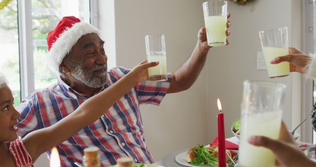 Happy african american multi generation family wearing santa hats and celebrating holiday meal. family christmas time and festivity together at home.