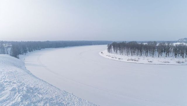 Winter river curving through snow-covered park, aerial minimalist frozen landscape