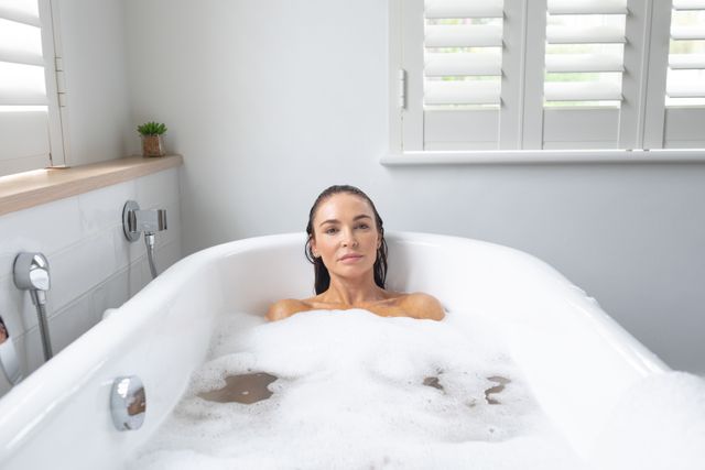 Portrait of beautiful woman taking bubble bath in bathroom at home
