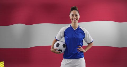 Confident female soccer player holding ball with austrian flag