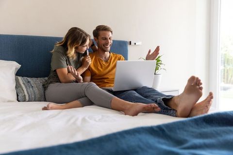 Couple Collaborating on Laptop in Cozy Bedroom Setting