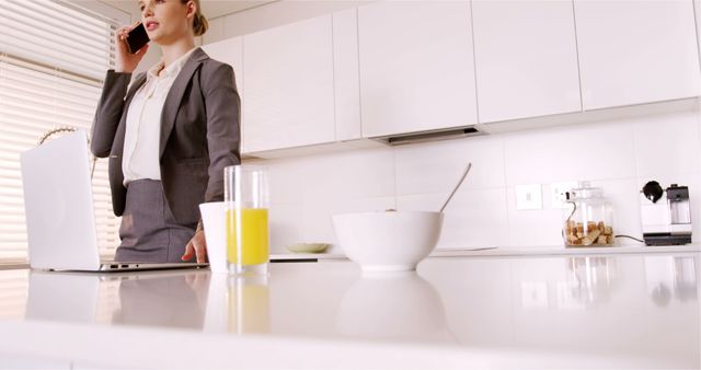 Businesswoman in kitchen using smartphone while working on laptop - Download Free Stock Images Pikwizard.com