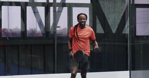 Athlete Enjoying Padel in Urban Glass Court Setting