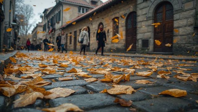 Swirling autumn leaves covering wet cobblestone street in historic lane