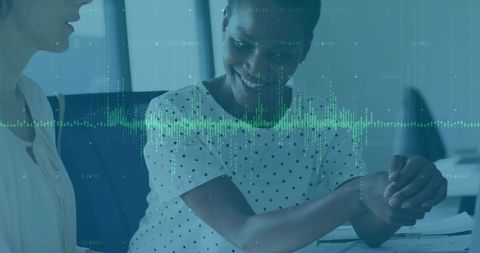 Smiling woman reviewing documents with green waveform overlay, collaborating at office table