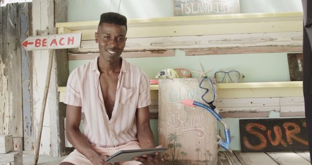 Portrait of happy african american man in surf shop on beach with tablet - Download Free Stock Photos Pikwizard.com