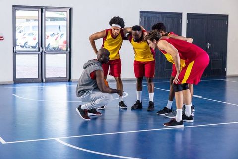 Diverse Basketball Team Huddling with Coach for Strategy Discussion