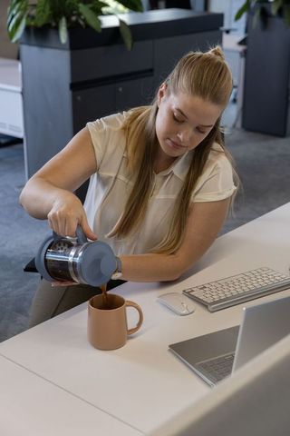 Woman Pouring Coffee at Modern Office Workspace