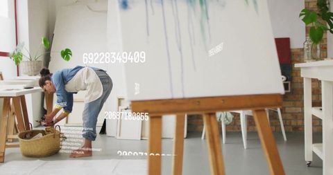 Artist working in creative art studio with easel and supplies