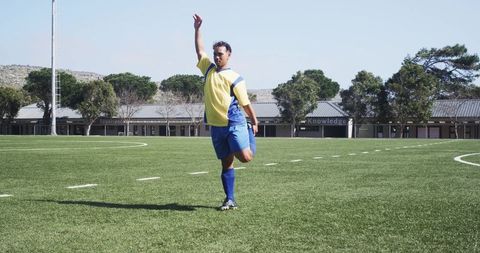 Soccer Player Stretching on Empty Field under Clear Sky