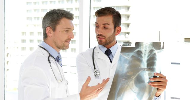 Two doctors discussing X-ray results in medical office - Download Free Stock Images Pikwizard.com