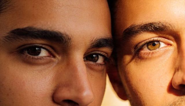 Pressing two male faces close with intense gaze and warm golden light