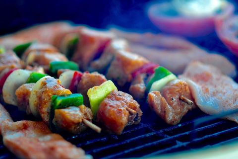 Sizzling chicken kebabs and marinated cutlets grilling on barbecue closeup