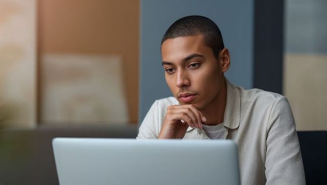 Young man concentrating on laptop, remote work portrait for business and education