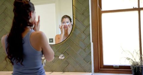 Teenage girl applying under eye masks for skincare ritual