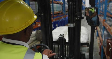 Forklift operator lifting pallet of white bulk bags in industrial warehouse aisle