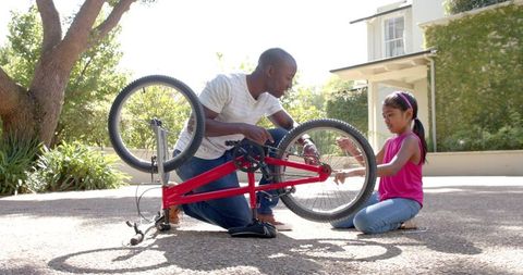 Man Teaching Girl Bicycle Repair Outdoors for Skill Building