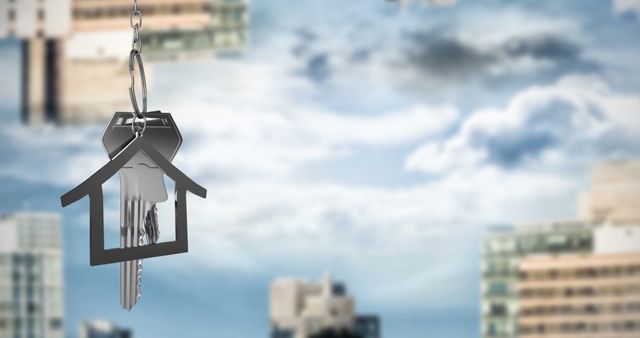 Focused house keys on keyring hanging against a background of blurred city buildings and cloudy sky. Use for real estate advertisements, home ownership promotions, or articles about urban living.