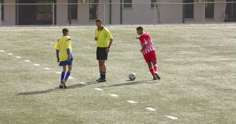 Two Youth Soccer Players Training with Referee on Grass Field