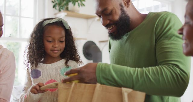 Image of happy african american parents with daughter and grandmother unpacking food shopping. Family, domestic life and togetherness concept digitally generated image.