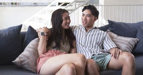 Young couple relaxing and cuddling on modern sofa in bright contemporary living room
