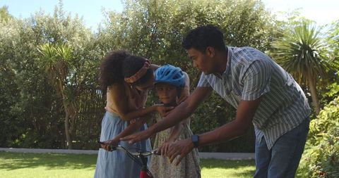 Parents Teaching Daughter to Ride Bike in Sunny Park
