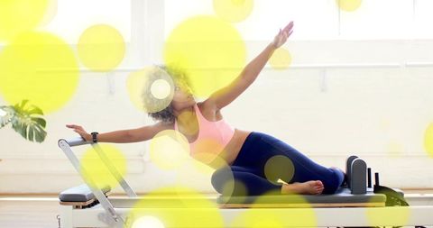 Pilates reformer stretching and balancing with yellow bokeh in bright studio