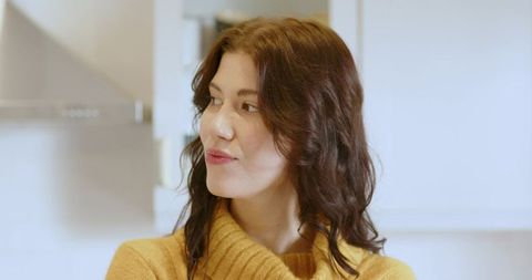 Woman in modern kitchen looking away contemplatively