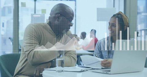 Senior professional mentoring young colleague reviewing reports with data charts overlay