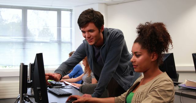 This image shows students collaborating on a computer project in a classroom environment. It can be used to depict educational teamwork, digital learning, and modern education techniques. Ideal for educational websites, brochures, and promotional materials targeting learning institutions, workshops, and student engagement.