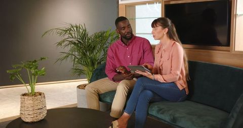 Diverse Colleagues Discussing Work Using Tablet on Office Couch