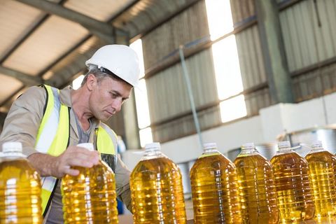 Quality Control Worker Inspecting Bottles in Industrial Warehouse