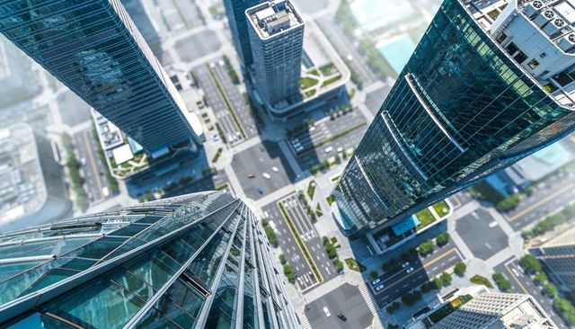 Soaring glass skyscrapers with curved facades over urban intersection, aerial city skyline
