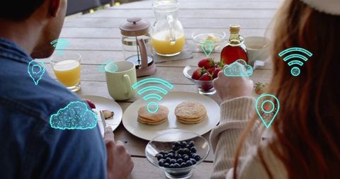 Couple enjoying augmented breakfast on deck, wearing casual knit beanie and eating pancakes