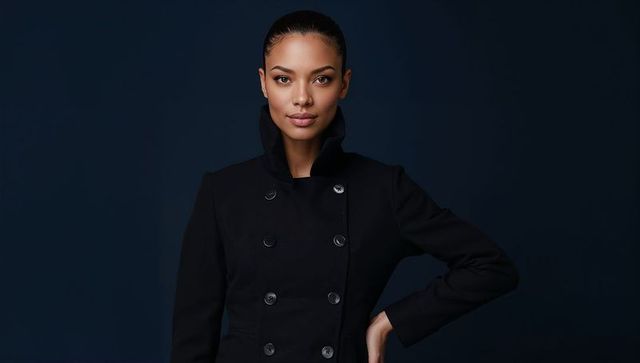 Confident female model posing in tailored black double-breasted coat with raised chin