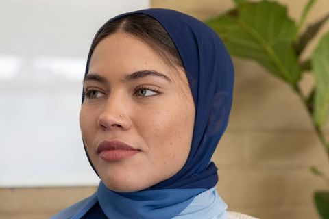 Contemplative muslim woman wearing navy and light blue hijab in modern office portrait