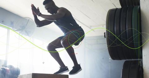 Explosive box jump by athlete powering through plyometric training in industrial gym space