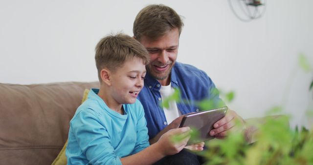 Father and Son Enjoying Tablet Together on Couch at Home - Download Free Stock Images Pikwizard.com